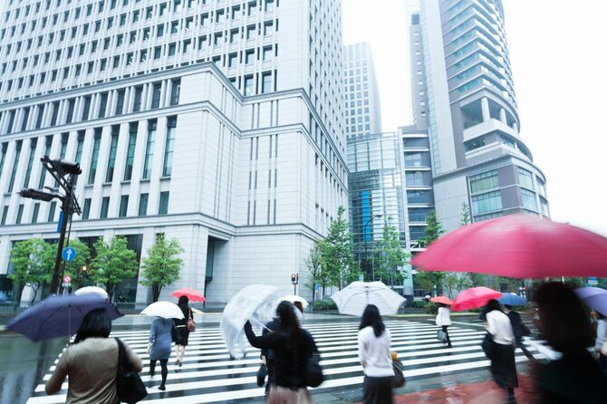 雨の朝の横断歩道を歩く日本のビジネスウーマン