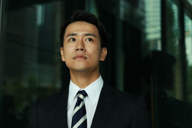 オフィスビルの外に立つ若いビジネスマン