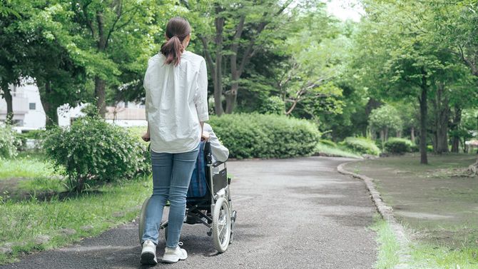 公園で車椅子を押す若い女性