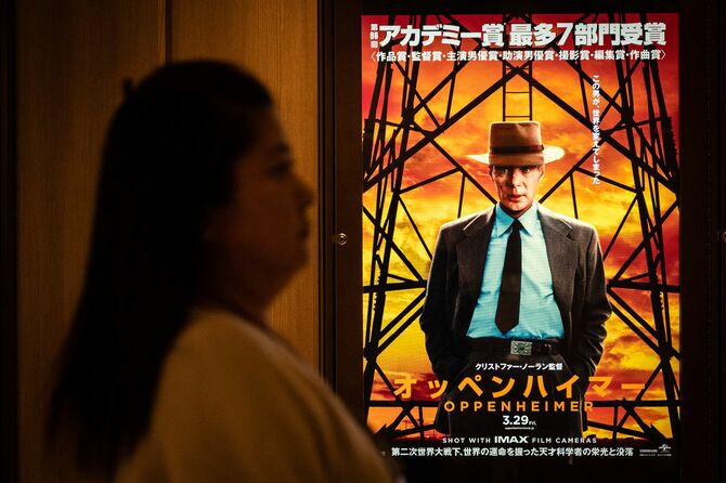 2024年3月29日、東京で映画『オッペンハイマー』のポスターの前を通り過ぎる女性